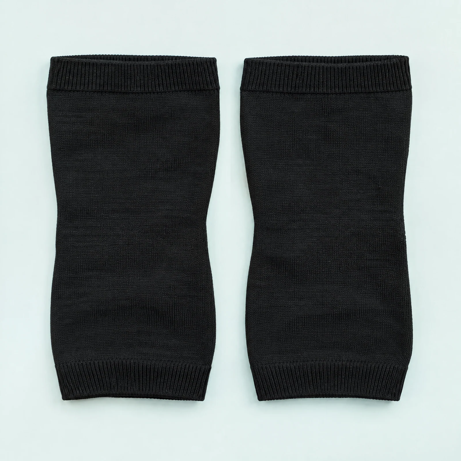 Pair of black knit knee support sleeves laid flat